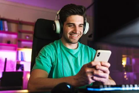 Image of caucasian smiling man using cellphone playing video game Stock Photos