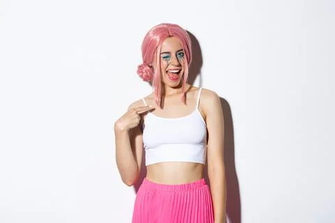 Image of cheeky pretty girl in pink wig and party outfit, winking and pointing Stock Photos