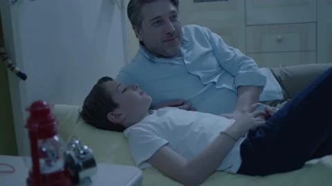 Image of cheerful father lying in bed with little son. Stock Footage 198376894