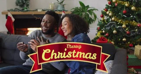 Image of christmas greetings text over biracial couple using smartphone at Ilustração Stock
