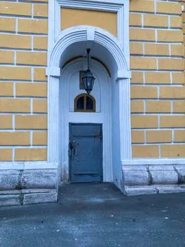 Image of a classical building with an arched, yellow-painted metal door under Stock Photos