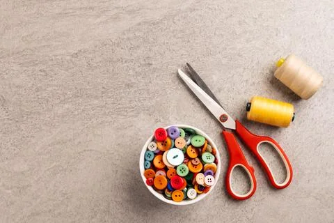 Image of close up of scissors, buttons and threads and copy space on cream 写真素材