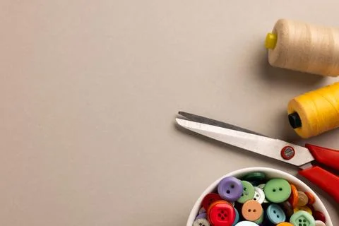 Image of close up of scissors, buttons and threads and copy space on cream 写真素材