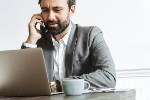 Image closeup of brooding concentrated businessman using laptop and talking o Stock Photos