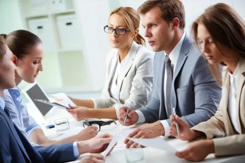 Image of confident man explaining something to his colleague at meeting Stock Photos