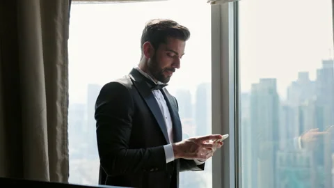 Image Of Confident Man. He Is Standing By The Window. Man Holding Mobile Phone. Stock Footage 153702806