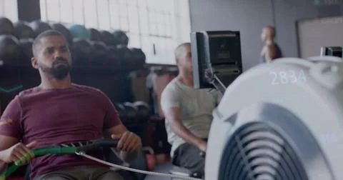 Image of data processing on graph over diverse men training on rowing machines Stockfoto's