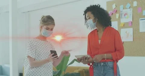 Image of data processing over businesswomen wearing face masks Foto stock