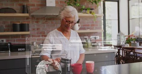 Image of data processing over senior african american woman preparing coffee in Stock-Fotos