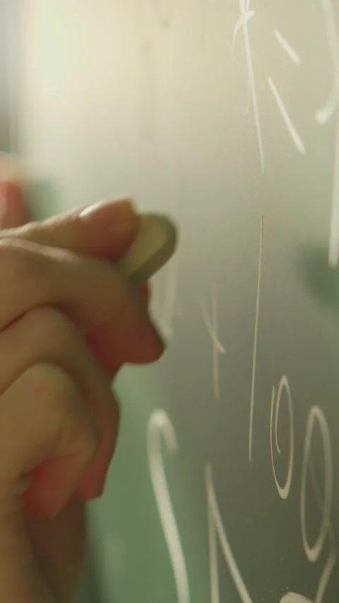 The image depicts a closeup of a hand writing mathematical equations on a Stock Footage 282909842