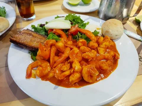 Image of a deviled shrimp dish accompanied with salad and bread Stock Photos