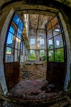 The image is of a dilapidated building with a large open door Foto stock