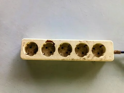 Image of a dirty, but still functioning, socket on a table with a few cables Stock Photos