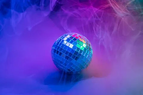Image of a disco ball within a vibrant, colorful smoke swirl, evoking festi.. Stock Photos