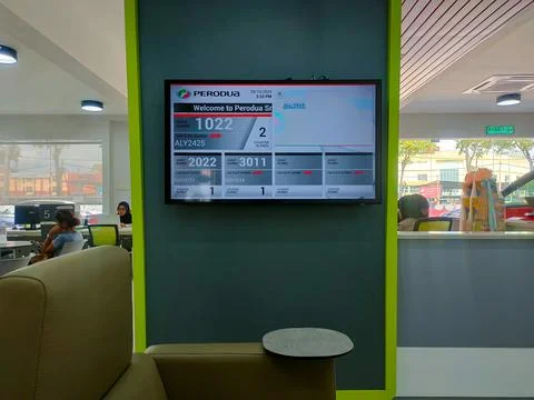 The image displays a digital queue management system at a Perodua service c.. 스톡 사진
