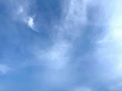Image displays an open light blue sky with thin, wispy white clouds spread ac Foto stock