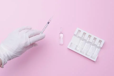 Image of a doctor's hand in a white protective medical glove holding a syring Foto stock