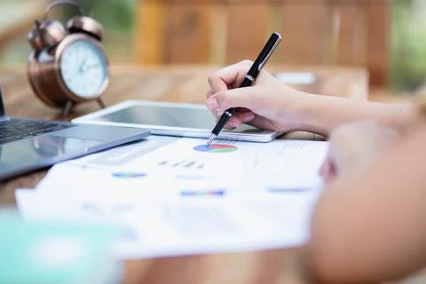 Image of document with charts on background of male and female working , busi Stock Photos