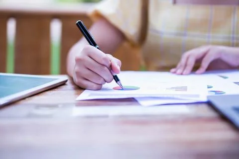 Image of document with charts on background of male and female working , busi Stock Photos