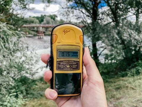 Image of a dosimeter in hand against the background of a natural area with a Stock Photos
