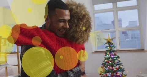 Image of dots moving over african american couple embracing under christmas tree Ilustração Stock