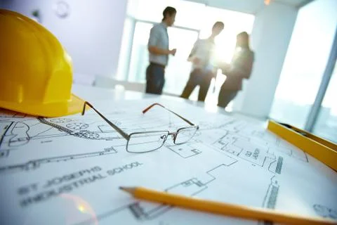 Image of engineering objects on workplace with three partners interacting on bac Stock Photos