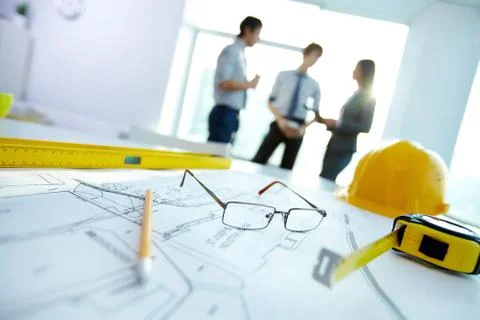 Image of engineering objects on workplace with three partners interacting on bac Stock Photos