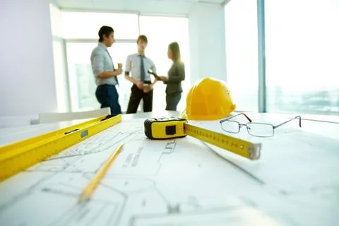 Image of engineering objects on workplace with three partners interacting on bac Stock Photos