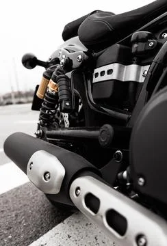 The image features a close-up view of a black motorcycle parked on a road wit Fotos de archivo