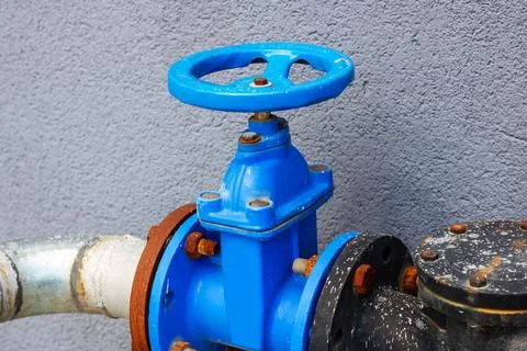 This image features a closeup view of a blue valve situated on a pipe Stock Photos