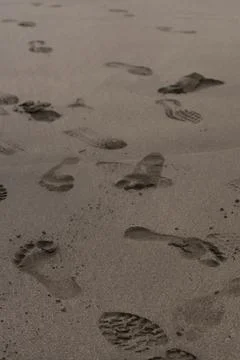 The image features a collection of footprints in the sand on a beach. The foo Foto stock