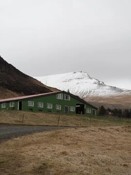 This image features a large green building in the foreground with a rugged .. Fotos de archivo