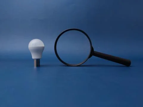 This image features a light bulb positioned on top of a magnifying glass ag.. Фото