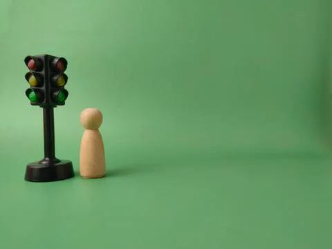 The image features a mini traffic light toy and a wooden peg doll on a gree.. Stock Photos