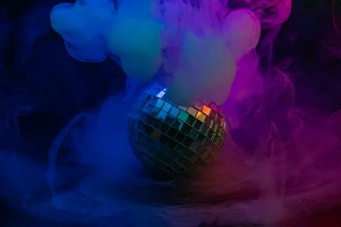 Image features a vibrant disco scene with a disco ball, colorful smoke, and.. Stock Photos
