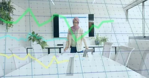 Image of financial data processing over biracial businesswoman in hijab working Foto stock