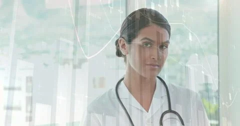 Image of financial data processing over caucasian female doctor using tablet Foto stock
