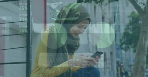 Image of financial data processing over biracial woman in hijab using smartphone Foto stock