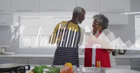 Image of financial data processing over biracial senior couple in kitchen Stock Photos