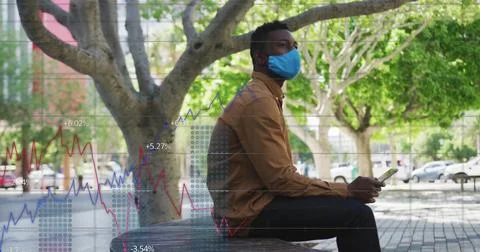 Image of financial data processing over african american man wearing face mask Foto stock