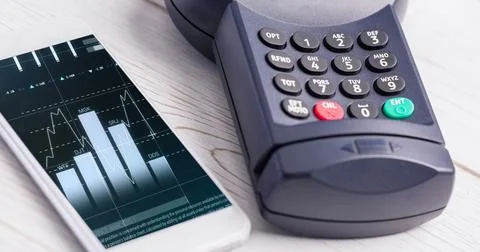 Image of financial data processing on smartphone next to credit card terminala 스톡 사진