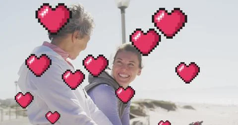 Image of floating red pixel hearts, over happy women talking on beach 写真素材