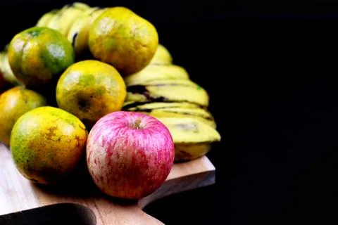 Image of focused apple in group of fruit on the cutting board with black back 写真素材