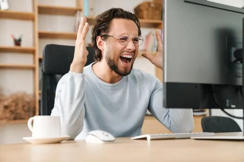Image of furious bearded programmer man screaming working with computer Stock Photos
