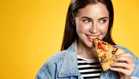 Image of girl smiling while biting slice of pizza, happy face at pizzeria Stock Photos