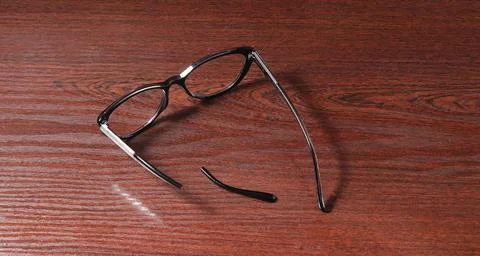 An image of glasses with a broken headband lying on a table. Stock Photos