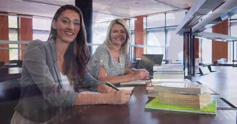 Image of globe and programming language over smiling caucasian teachers sitting Photos