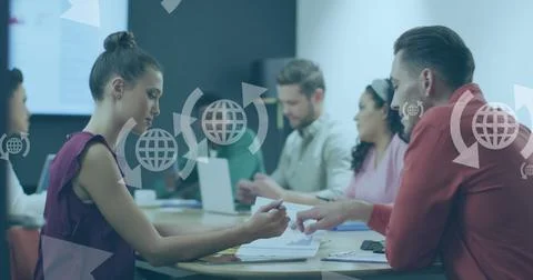 Image of globe with arrows icons over diverse business people at meeting in.. Stock Photos