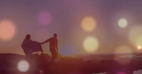 Image of glowing spots over diverse couple holding hands Fotos Stock