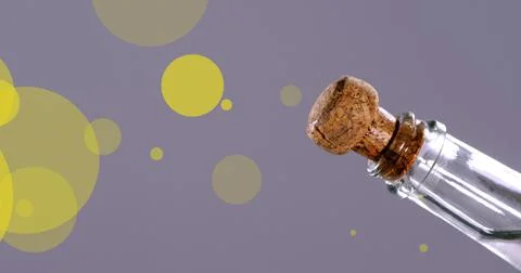 Image of glowing yellow spots falling over champagne cork exploding from bottle Foto stock
